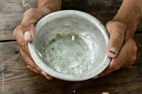 The poor old man's hands hold an empty bowl of beg you for help. The concept of hunger or poverty. Selective focus. Poverty in retirement. Alms photo