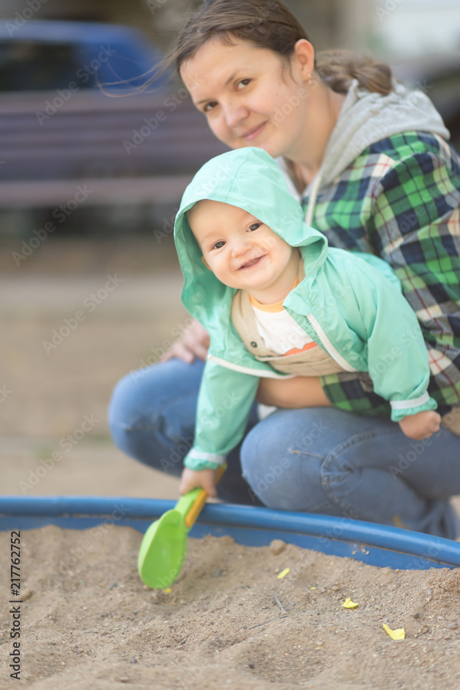 mother and child play in sandbox with green scoop mother and child play in sandbox with green scoop