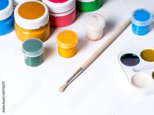 Jars with paint for drawing and brush on a white background
