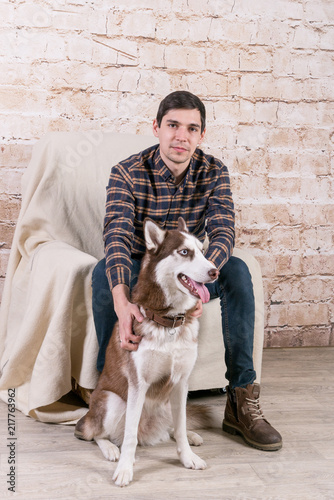 A man and a hussy dog are posing in the studio. The basics of training pets.