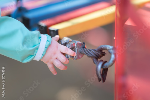 Detail of steel bolt anchor eye in metal. The end knot of steel rope. Mount colored suspension bridge in the Playground. Children's hand touches a metal nut photo