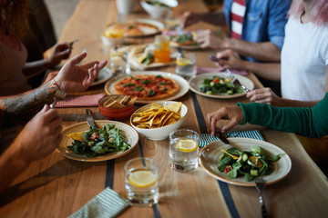 Human hands over plates with food during talk by dinner in modern cafe or restaurant
