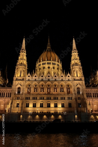 Panoramic view of the Hungarian parliament with illumination of walls from Danube at night.
