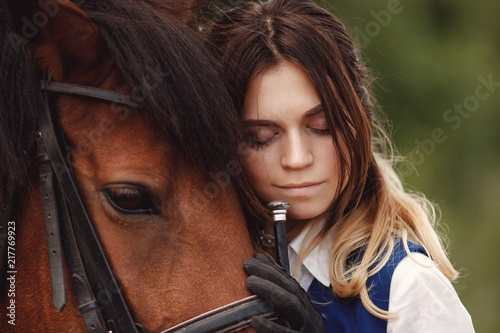 Young woman rider hugging with brown horse, eyes closed. Concept friends