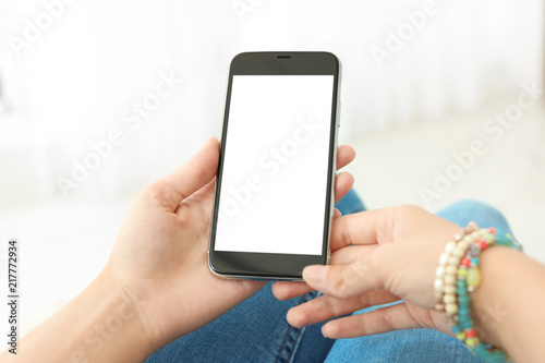 Woman holding smartphone with blank screen on light background. Mockup for design