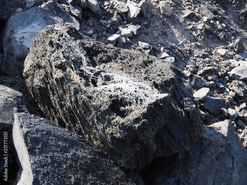 Textured Obsidian and hardened lava rock on a sunny fall day at the Big Obsidian Flow in the Newberry National Volcanic Monument in Central Oregon.  photo