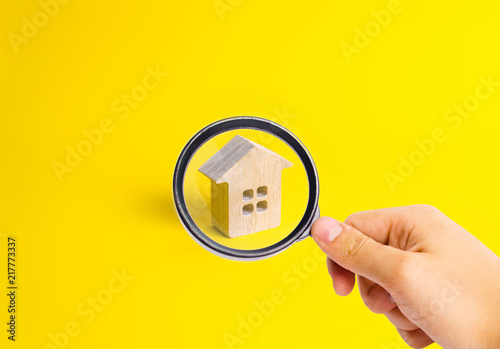 A small wooden house stands on a yellow background. The concept of buying and selling real estate, renting. Search for a house. Affordable housing, credit and loans. Investments in business