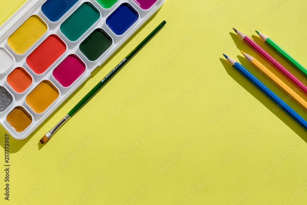Fototapeta premium Artist home office desk. yellow Paper with watercolors paint brush isolated. Flat lay,creative minimal mock up template.School supplies. set of new watercolor paints.Copy space