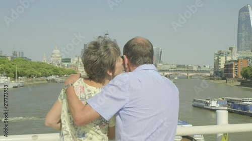 Active senior caucasian tourist couple looking at a map on waterloo bridge london with the river thames and london skyline behind while on vacation themes of sightseeing active seniors love togetherne