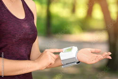 Young woman checking pulse outdoors on sunny day
