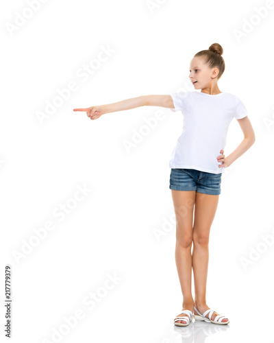 A little girl in a white T-shirt is pointing at something.