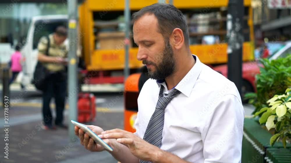 Businessman working on tablet computer by the street
Businessman working on tablet computer by the street