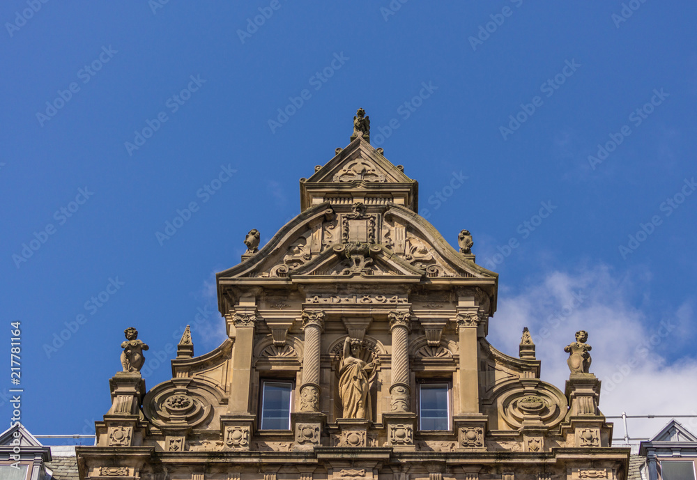 Edinburgh, Scotland, UK - June 13, 2012: Top niche of monumental brown stone facade of Department store on corner of Princess and South David streets under blue sky.
