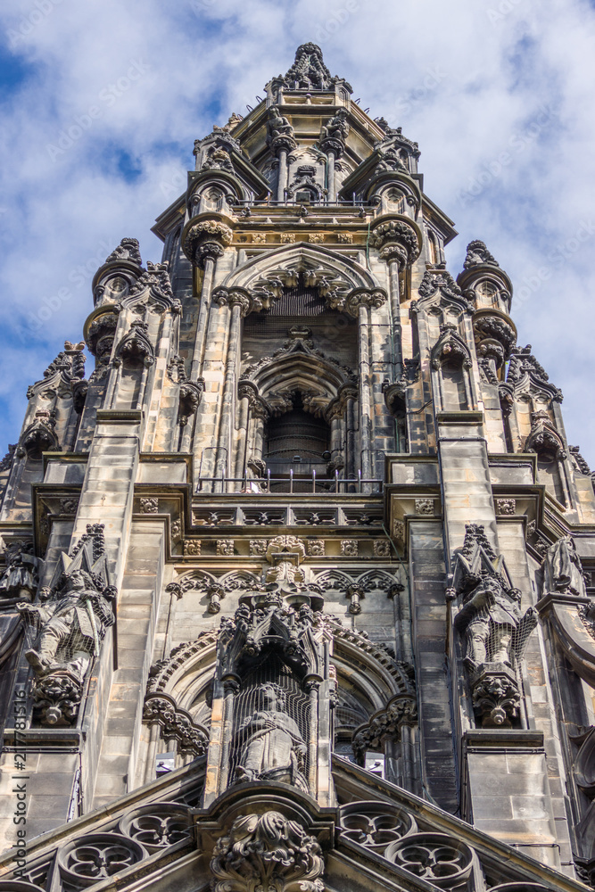 Edinburgh, Scotland, UK - June 13, 2012: Closeup of Scott Monument spire with niches and statues, all against blue sky broken by white clouds.