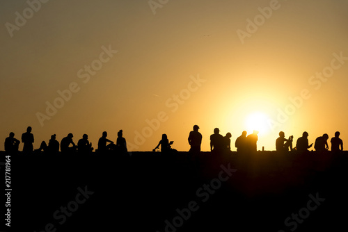 Silhouette peoples sitting on fortress wall enjoying in sunset. Tourist people at Kalemegdan, Serbia. 