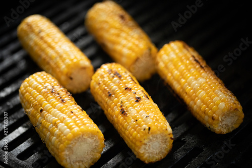 Corn on the cob roasting on black barbecue grill grates