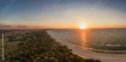 Fototapeta Naklejka Na Ścianę i Meble -  A fascinating red colored, clear sunset at a white beach of the Baltic Sea made by a drone up in the air