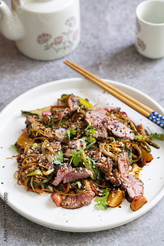 Asian stir fry beef fillet with rice noodles, bok choi, zucchini, radishes and sesame seeds