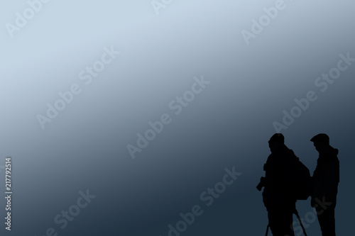 silhouette of 2 photographers against a blue background