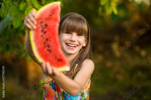 Happy child girl eats watermelon in summer