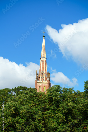 Saint Gertrude Old Church seen above trees and bright blue sky, Riga, Latvia. July 20, 2018 photo