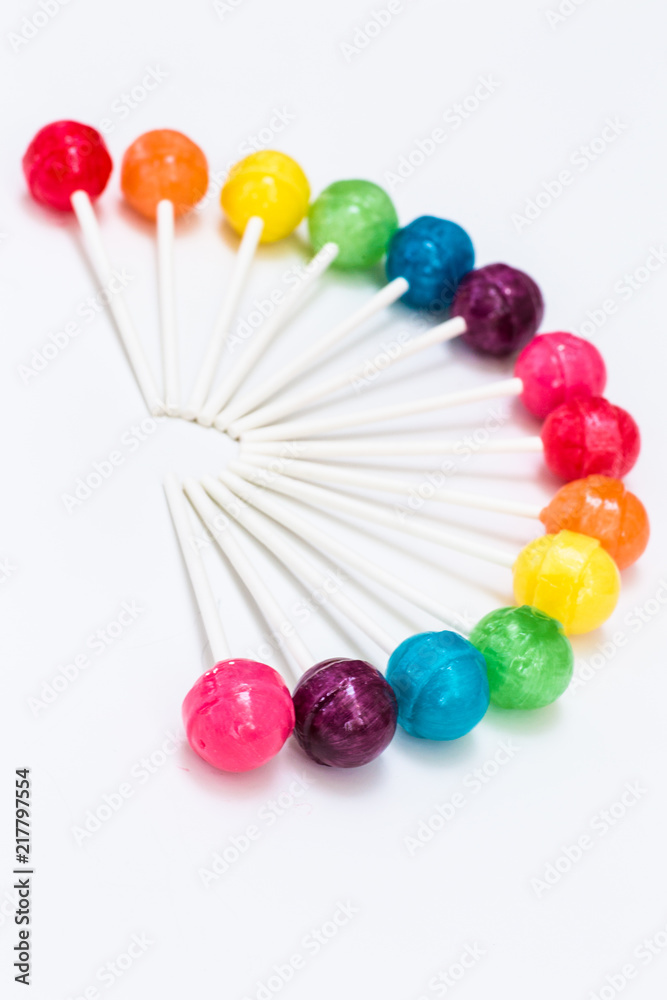Rainbow design of sweet colorful lollipops against white background 