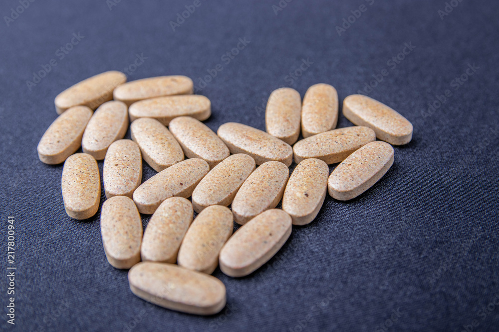 oval brown pills on a dark blue background in the form of the heart oval brown pills on a dark blue background in the form of the heart