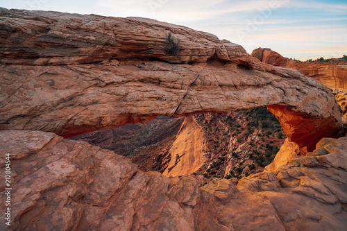 Cliff's-edge sandstone Mesa Arch framing an iconic sunrise view of the red rock canyon landscape below.