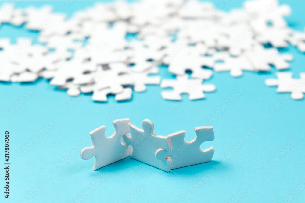 Three pieces of white jigsaw puzzle with the rest at the background Three pieces of white jigsaw puzzle with the rest at the background