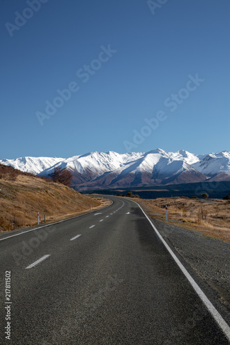 Curved road leading to snow capped mountains
