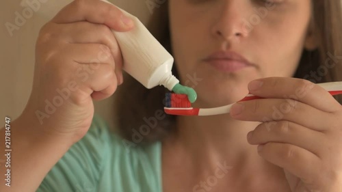 Young girl with beautiful white teeth squeezes toothpaste out of tube, cleans her teeth. Close up photo