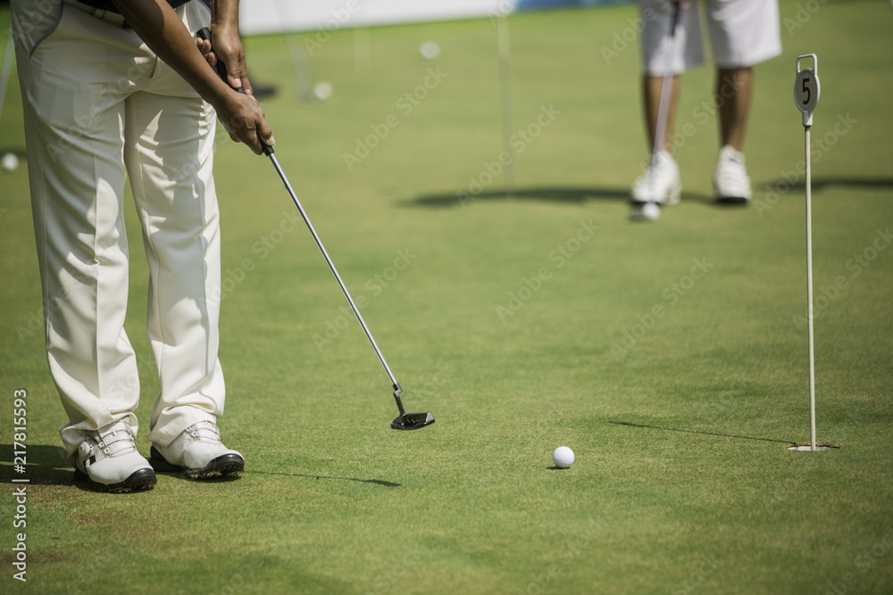 Obraz premium Golf player at the putting green hitting ball into a hole