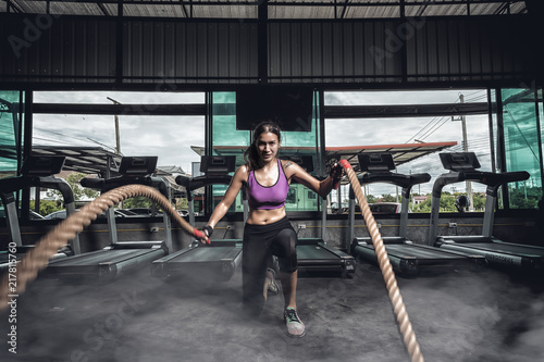  young fitness female exercising with rope at a gym. Young woman pulling rope at gym. © FAMILY STOCK