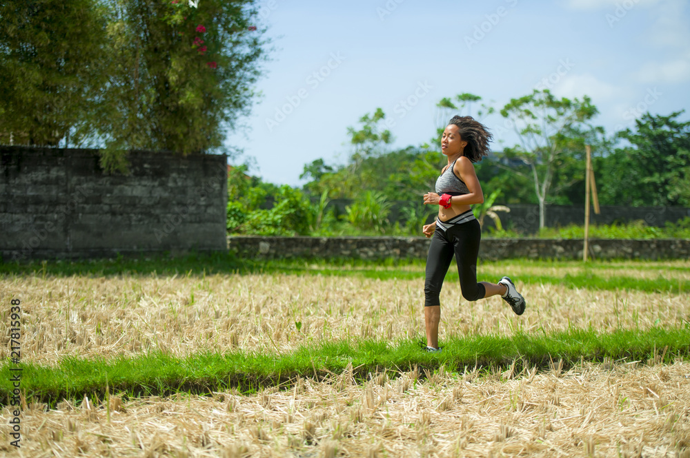 healthy lifestyle portrait of young happy and fit Asian Chinese runner woman in running workout outdoors at green field background in body fitness concept