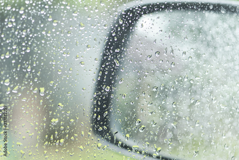 Raindrops on car window and car mirror on a rainy day