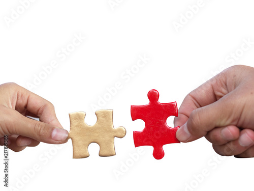 hands holding piece of gold and red jigsaw puzzle on white background