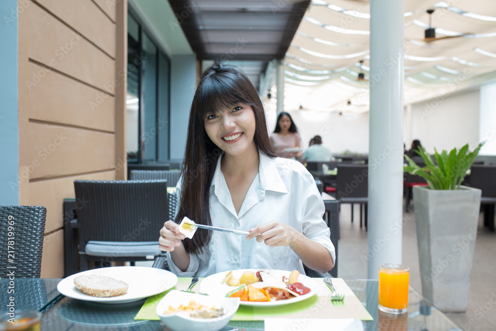 Young beautiful girl enjoy and relaxing  her breakfast in the outdoor atmosphere restaurant, Thailand