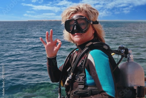 Woman scuba diver ready to jump into the sea showing signal OK