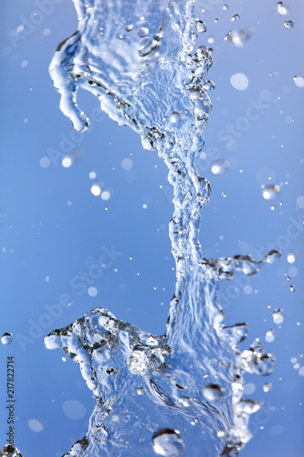 Splashing water with drops on the sky background