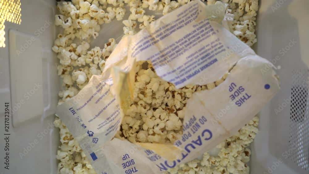 Exploded popped popcorn bag rotating in microwave. Making popcorn in a