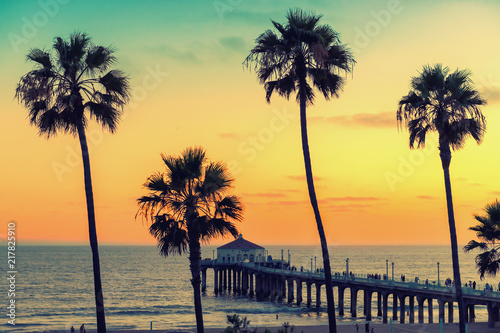 Palm trees on Manhattan Beach and pier at sunset in Los Angeles, California. Vintage processed. Fashion travel and tropical beach concept. 