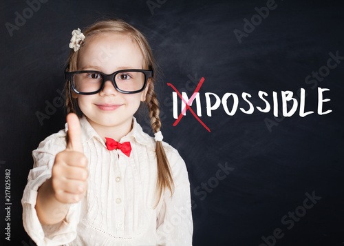 Smart child with thumb up and putting a cross over impossible on blackboard background