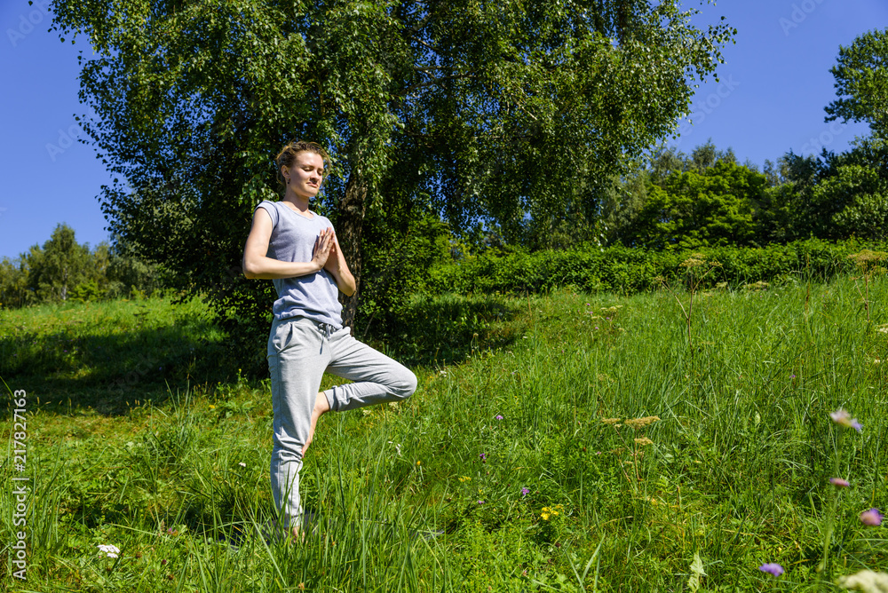 Young attractive woman practicing yoga outdoors on a sunny day, Vrikshasana (tree pose) Young attractive woman practicing yoga outdoors on a sunny day, Vrikshasana (tree pose)