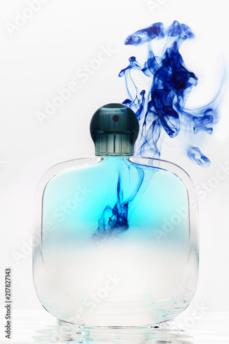 Bottle of female perfume on a background of blue spots of a solution. photo