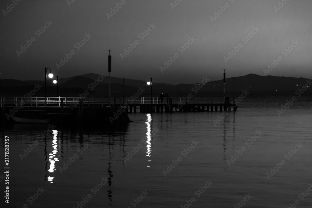 Some people on a pier at Trasimeno lake (Umbria, Italy) at dusk