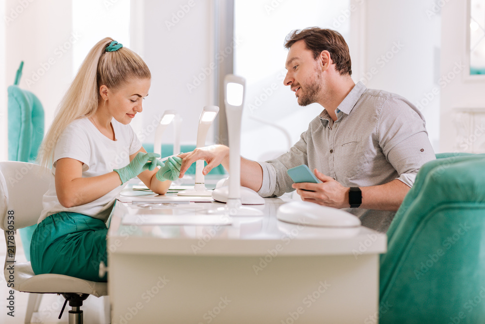 Talking to master. Attractive metrosexual feeling relaxed and contended while talking to his favorite nail master Talking to master. Attractive metrosexual feeling relaxed and contended while talking to his favorite nail master
