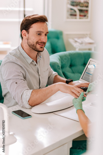 Manicure in salon. Bearded metrosexual businessman feeling relaxed while getting manicure in beauty salon photo