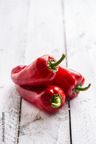Three ripe red peppers paprika on wooden board