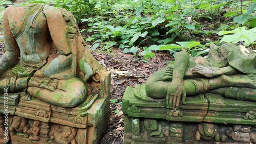 Buddha field of broken sculpture with beautiful ancient Buddha statue in middle of green nature, collection of old Buddha heads and busts covered with moss in Wat Umong temple in Chiang Mai, Thailand photo