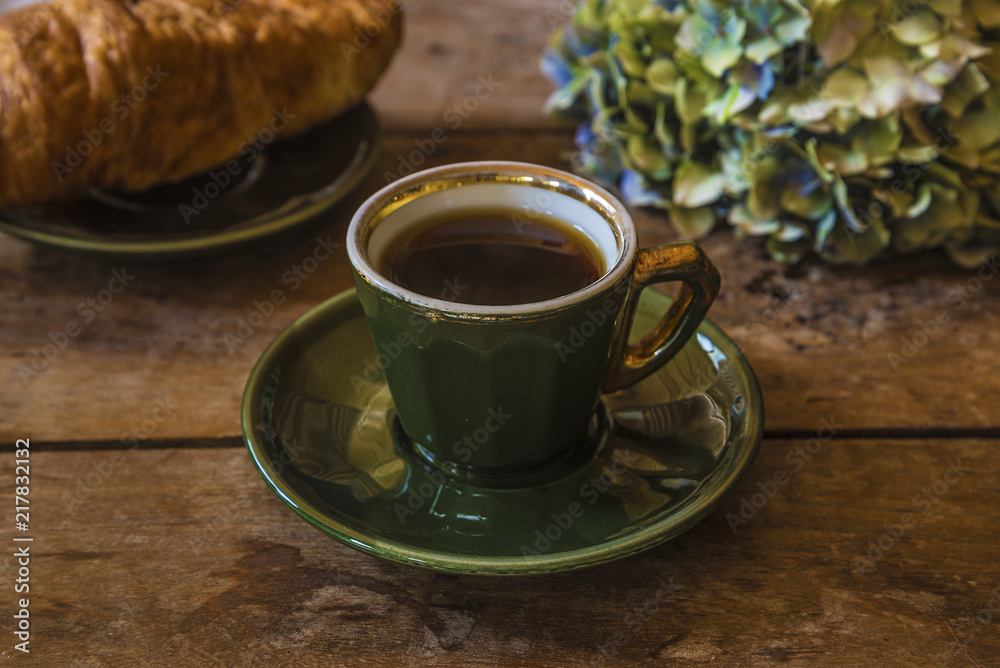 French breakfast in retro style: espresso in retro cup of parisian bistrot, croissant and hydrangea flower on old wooden background French breakfast in retro style: espresso in retro cup of parisian bistrot, croissant and hydrangea flower on old wooden background